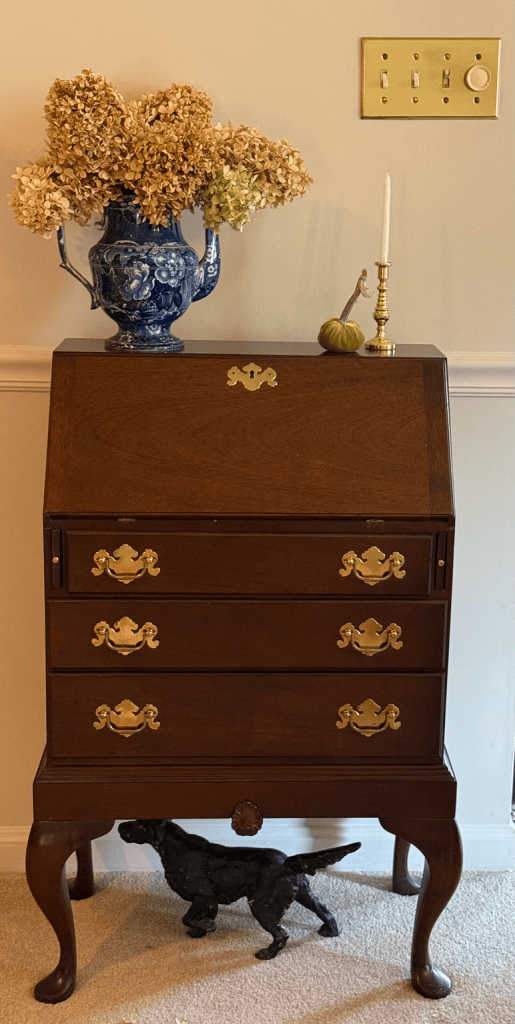 Antique blue-and-white pitcher filled with dried hydrangeas on my mother’s writing desk, with an iron pointer dog beneath it.