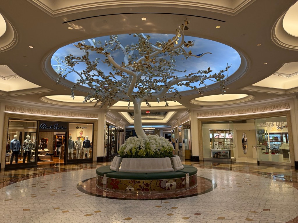 Decorative tree with glistening gold flowers beneath a circular skylight in The Venetian’s shopping area.