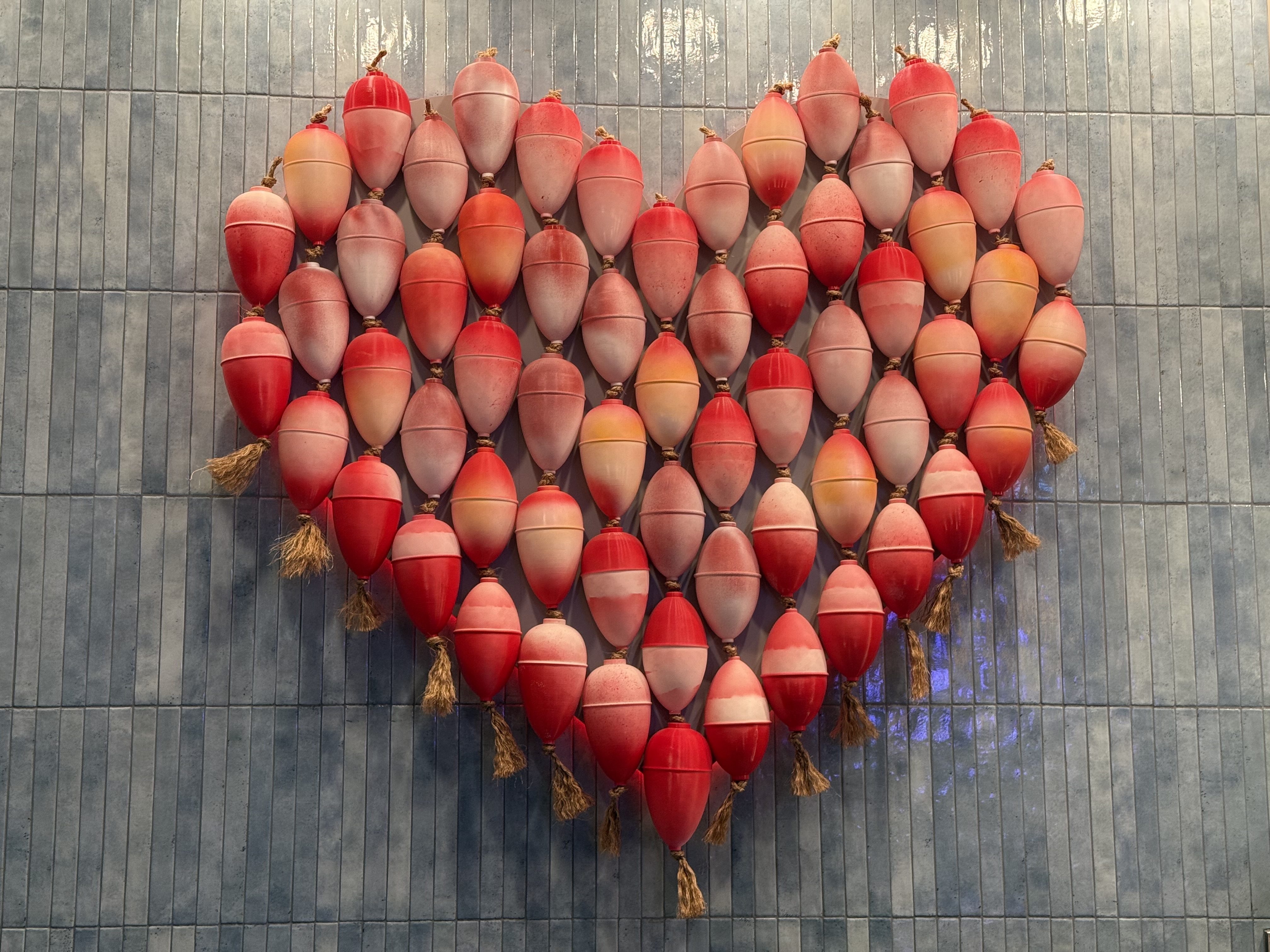 Red, orange, and pink buoys arranged in a heart shape on a gray wall at a lobster restaurant in Miracle Mile Shops, Las Vegas.
